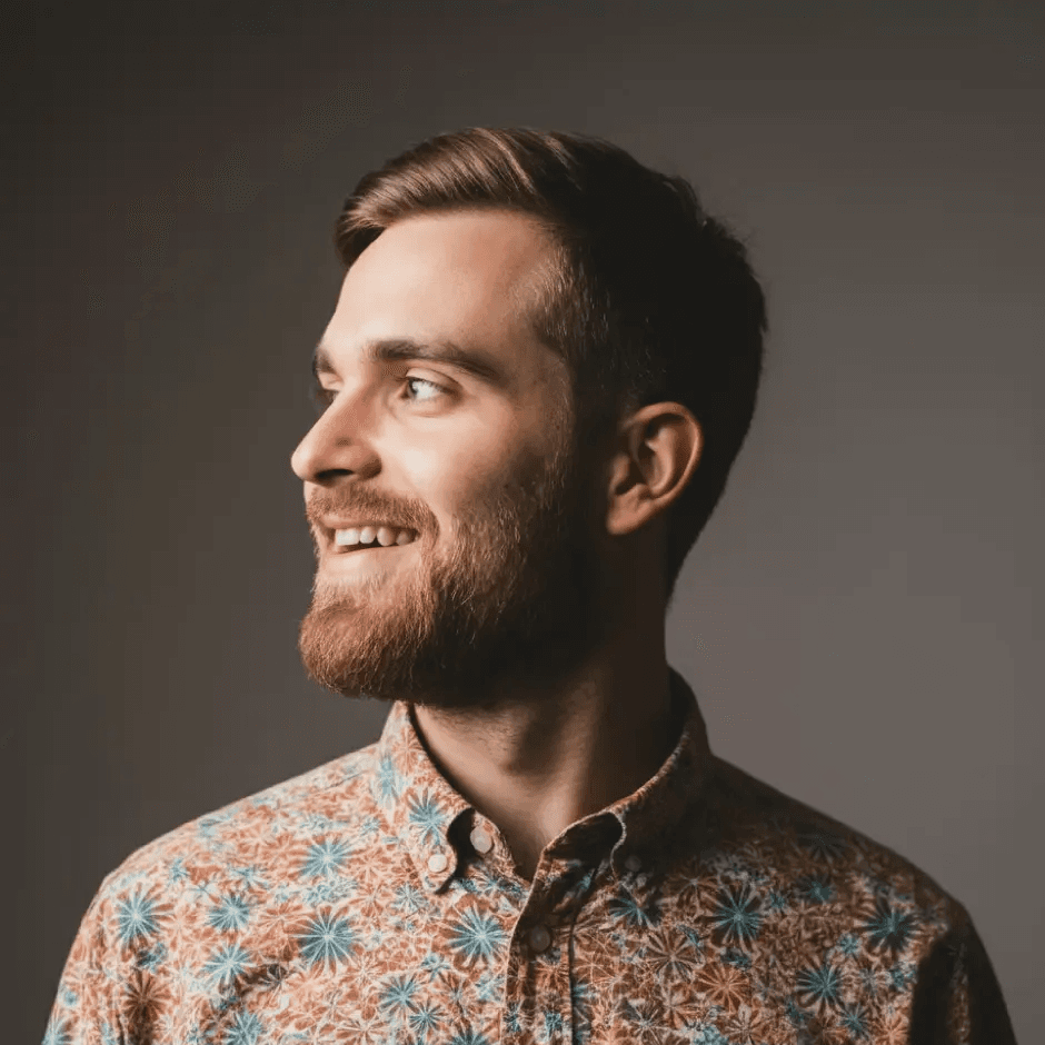 Portrait of man looking to the left and smiling with a dark background